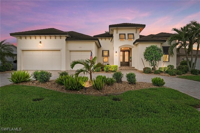 mediterranean / spanish-style home with a garage and a lawn