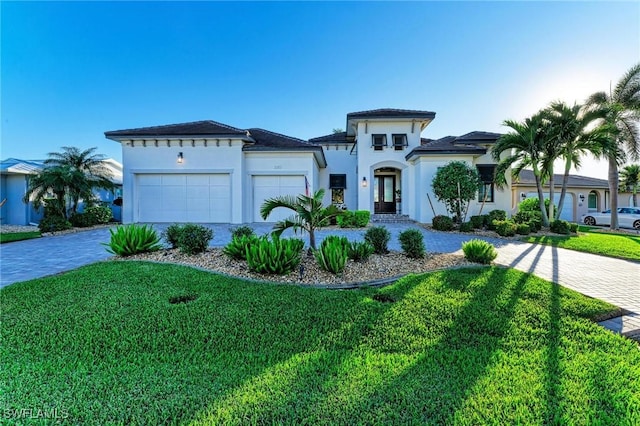 mediterranean / spanish home with a garage and a front lawn