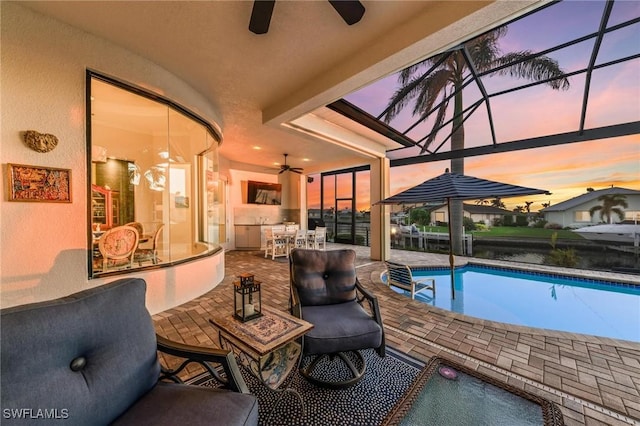 pool at dusk with a patio, a lanai, ceiling fan, and a bar