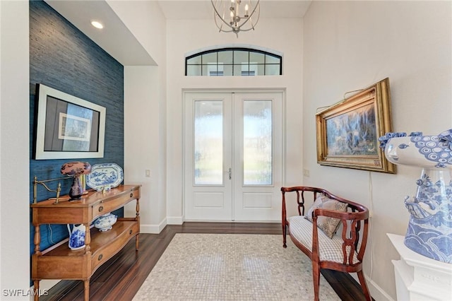 foyer entrance with french doors, an inviting chandelier, and dark wood-type flooring