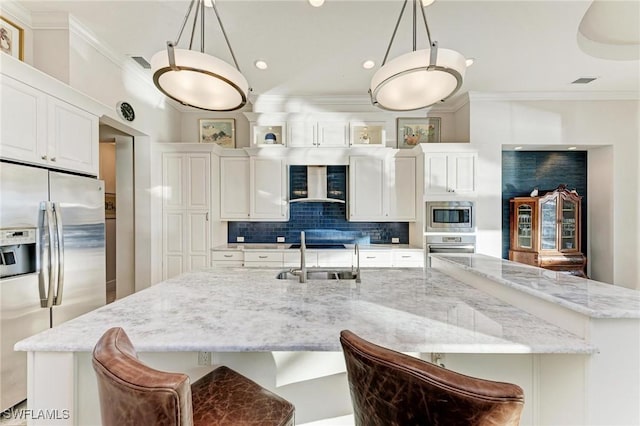 kitchen featuring appliances with stainless steel finishes, a kitchen bar, sink, and hanging light fixtures