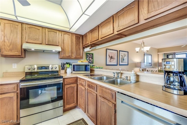 kitchen featuring sink, hanging light fixtures, light tile patterned floors, ceiling fan with notable chandelier, and appliances with stainless steel finishes