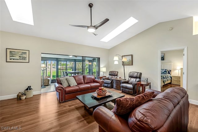 living room with vaulted ceiling with skylight, ceiling fan, and wood-type flooring