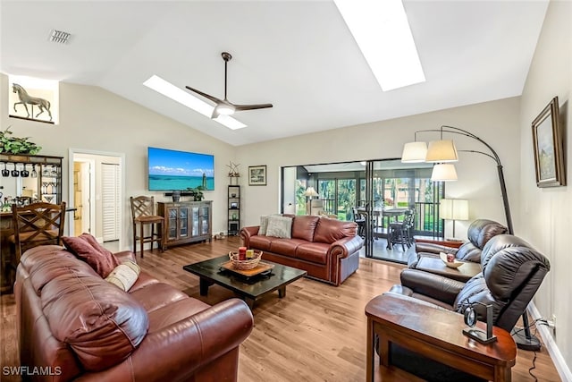 living room with light wood-type flooring, ceiling fan, and vaulted ceiling with skylight