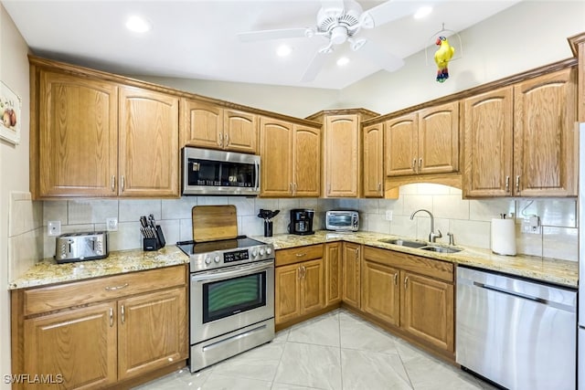 kitchen with tasteful backsplash, sink, lofted ceiling, and appliances with stainless steel finishes