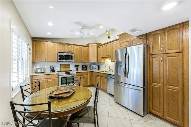 kitchen with appliances with stainless steel finishes, tasteful backsplash, ceiling fan, sink, and lofted ceiling