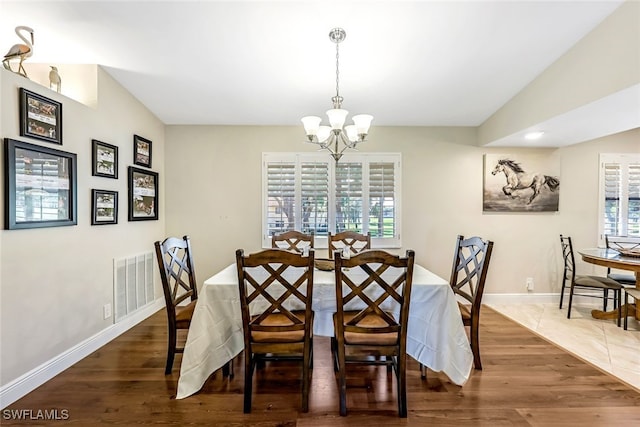 dining area with dark hardwood / wood-style floors, a wealth of natural light, and a chandelier