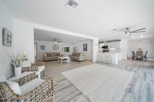 living room with ceiling fan and light wood-type flooring