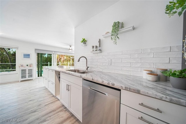 kitchen featuring white cabinets, sink, light hardwood / wood-style flooring, stainless steel dishwasher, and light stone counters