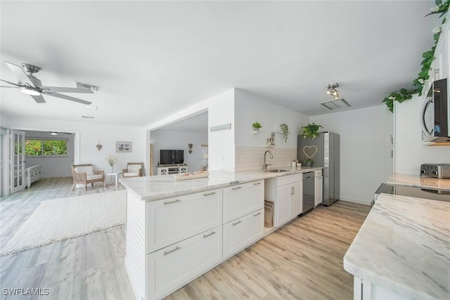 kitchen with kitchen peninsula, appliances with stainless steel finishes, sink, light hardwood / wood-style flooring, and white cabinetry