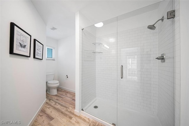 bathroom featuring a shower with door, wood-type flooring, and toilet