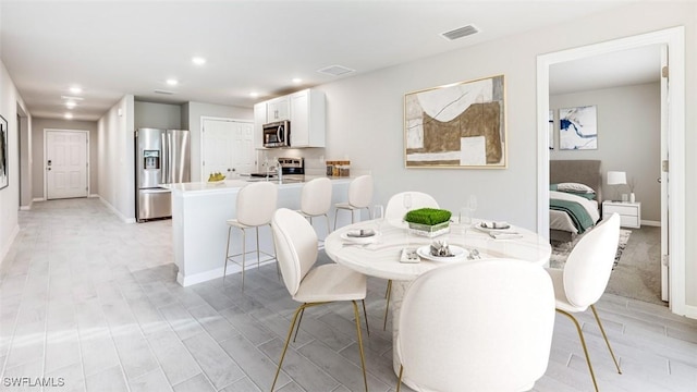 dining room with baseboards, light wood finished floors, visible vents, and recessed lighting