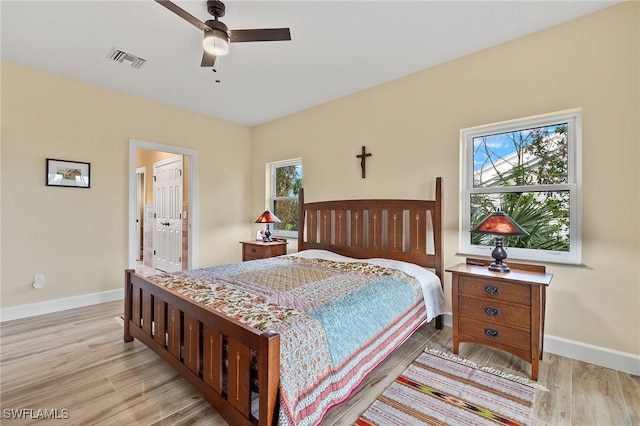 bedroom featuring light hardwood / wood-style floors, ceiling fan, and ensuite bathroom