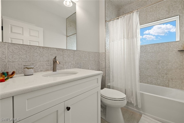 full bathroom with hardwood / wood-style floors, vanity, toilet, tile walls, and shower / tub combo with curtain