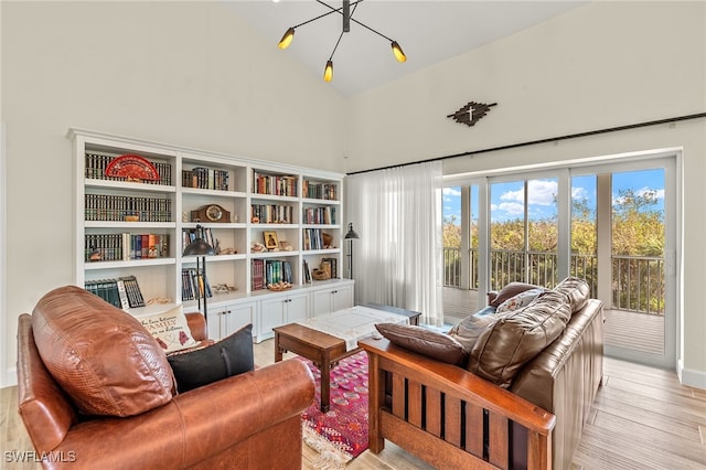 living area with an inviting chandelier, high vaulted ceiling, and light hardwood / wood-style flooring