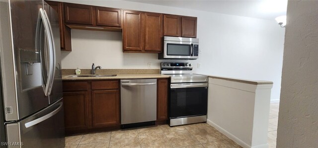 kitchen featuring light tile patterned floors, stainless steel appliances, and sink