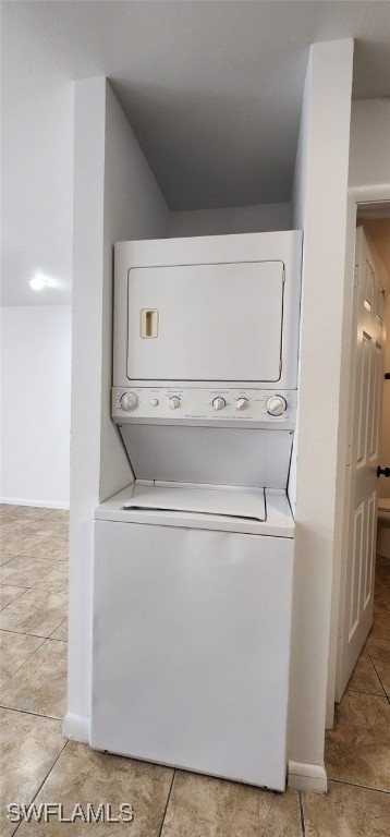 washroom with stacked washer / drying machine and light tile patterned flooring