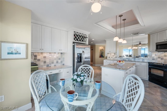 kitchen with appliances with stainless steel finishes, tasteful backsplash, a center island, white cabinetry, and hanging light fixtures