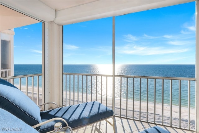 sunroom featuring a water view and a view of the beach