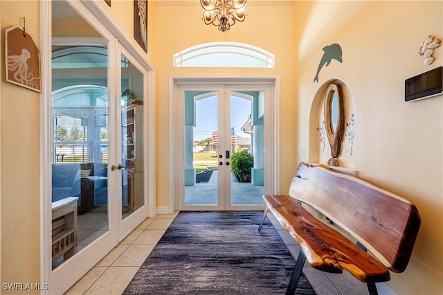 tiled entrance foyer with an inviting chandelier, a healthy amount of sunlight, and french doors