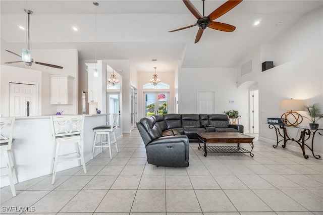 tiled living room with ceiling fan with notable chandelier and high vaulted ceiling