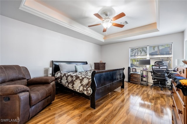 bedroom featuring a raised ceiling, hardwood / wood-style floors, and ceiling fan