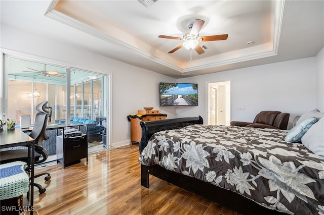 bedroom with hardwood / wood-style flooring, access to outside, a raised ceiling, and ceiling fan