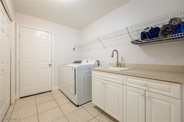 clothes washing area featuring cabinets, washing machine and dryer, sink, and light tile patterned floors