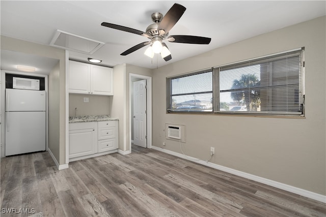 kitchen featuring a wall mounted air conditioner, white fridge, light wood-type flooring, and white cabinetry