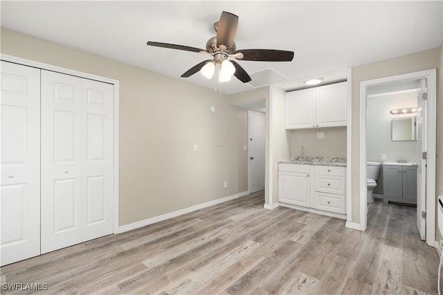 interior space featuring light stone countertops, ceiling fan, sink, light hardwood / wood-style flooring, and white cabinetry