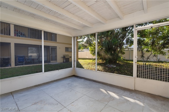 unfurnished sunroom featuring plenty of natural light, beamed ceiling, and wooden ceiling