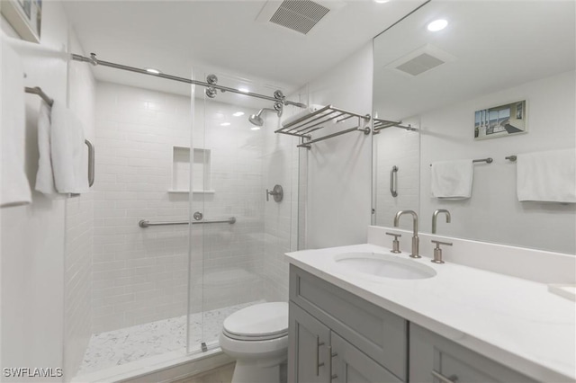 bathroom with vanity, toilet, and a shower with door