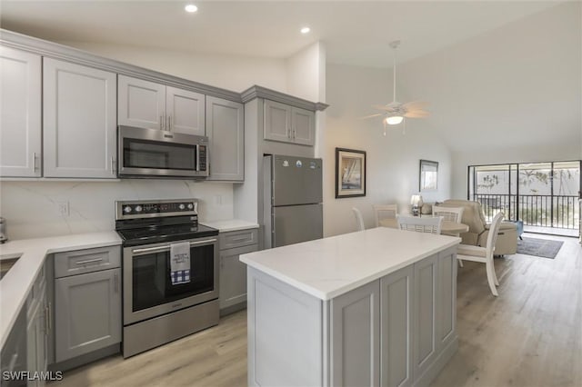 kitchen with gray cabinets, light wood-type flooring, stainless steel appliances, and vaulted ceiling