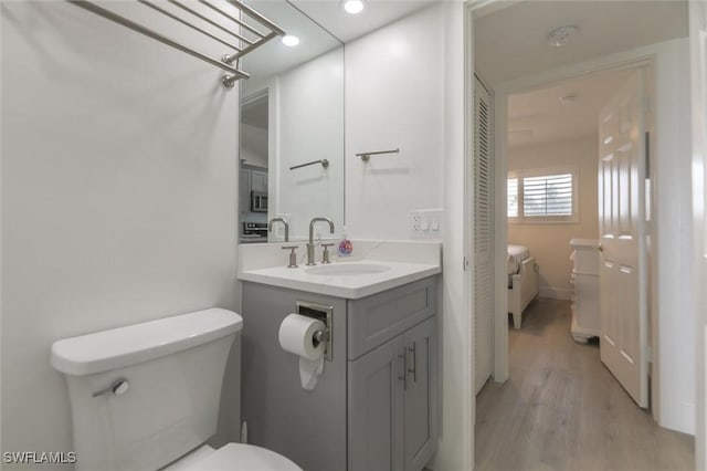 bathroom with hardwood / wood-style floors, vanity, and toilet