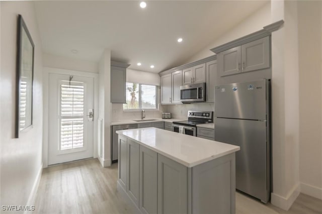 kitchen featuring gray cabinetry, sink, a center island, vaulted ceiling, and appliances with stainless steel finishes