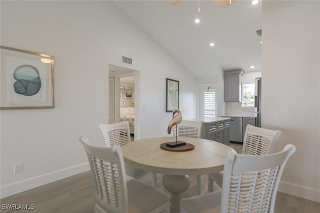 dining area with hardwood / wood-style floors and high vaulted ceiling