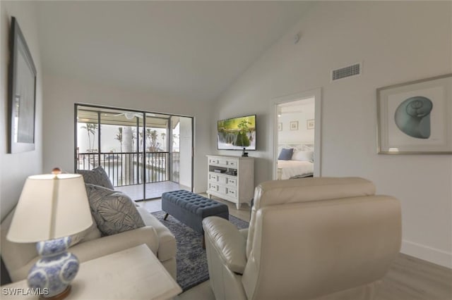 living room with high vaulted ceiling and light hardwood / wood-style floors