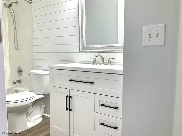 full bathroom featuring hardwood / wood-style floors, vanity, toilet, and tiled shower / bath combo