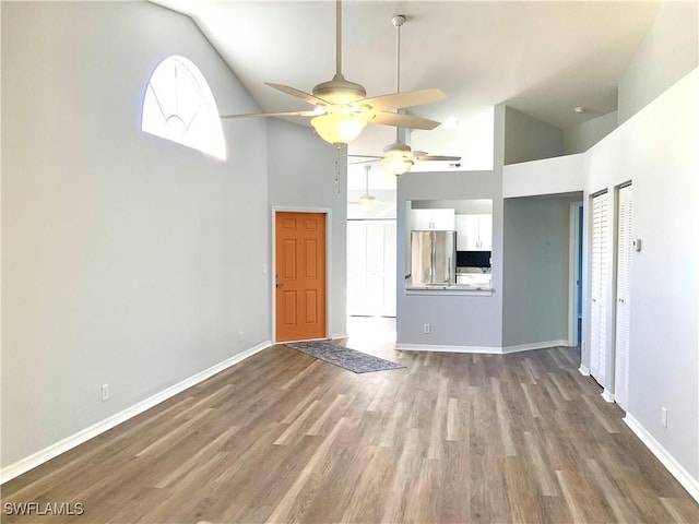 unfurnished living room featuring hardwood / wood-style flooring, high vaulted ceiling, and ceiling fan