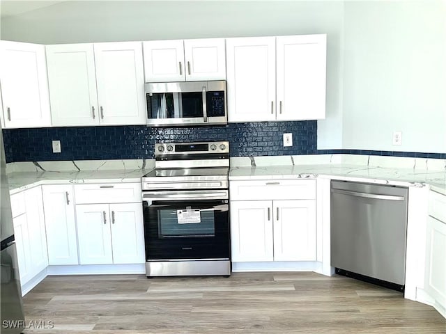 kitchen featuring white cabinets, stainless steel appliances, light stone countertops, and light hardwood / wood-style floors