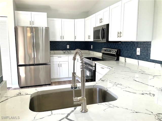 kitchen featuring white cabinetry, sink, stainless steel appliances, and light stone counters