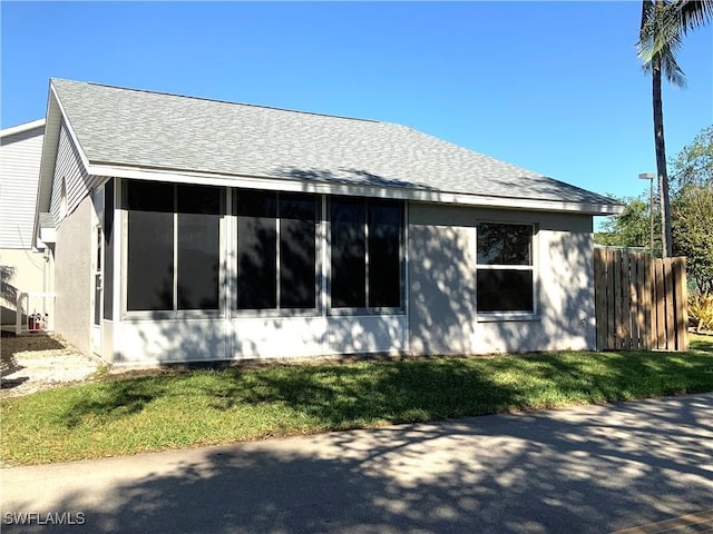 view of property exterior with a lawn and a sunroom