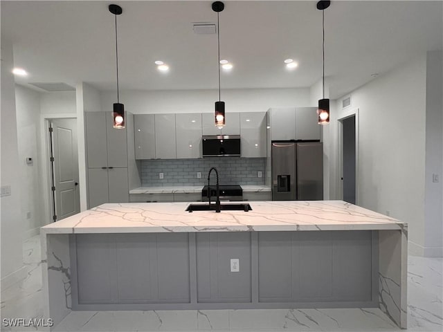 kitchen with light stone countertops, sink, stainless steel appliances, decorative light fixtures, and decorative backsplash