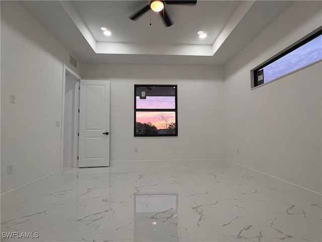 spare room featuring a tray ceiling and ceiling fan