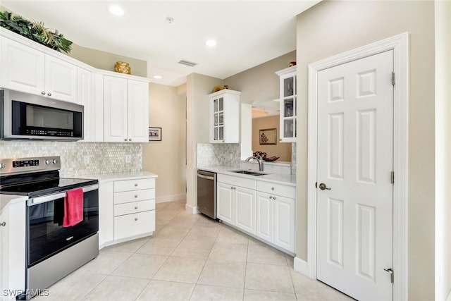 kitchen featuring appliances with stainless steel finishes, tasteful backsplash, sink, white cabinetry, and light tile patterned flooring