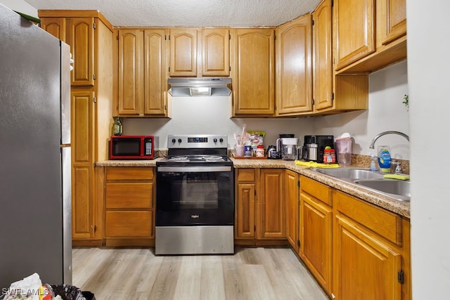 kitchen featuring sink, stainless steel appliances, a textured ceiling, and light wood-type flooring