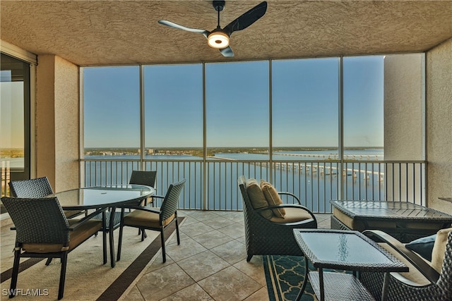 sunroom / solarium featuring ceiling fan and a water view