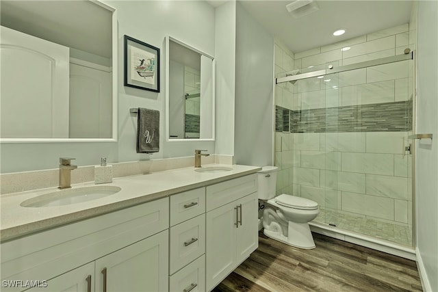 bathroom with hardwood / wood-style flooring, vanity, toilet, and walk in shower