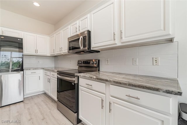 kitchen featuring light hardwood / wood-style flooring, tasteful backsplash, light stone counters, white cabinetry, and stainless steel appliances