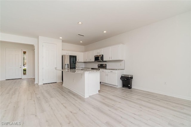 kitchen with stainless steel appliances, sink, a center island with sink, light hardwood / wood-style flooring, and white cabinetry